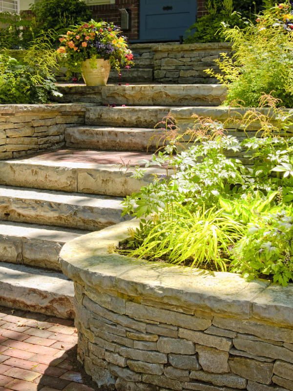 Elegant tiered stone retaining wall with steps and lush garden in Northwest Indiana.